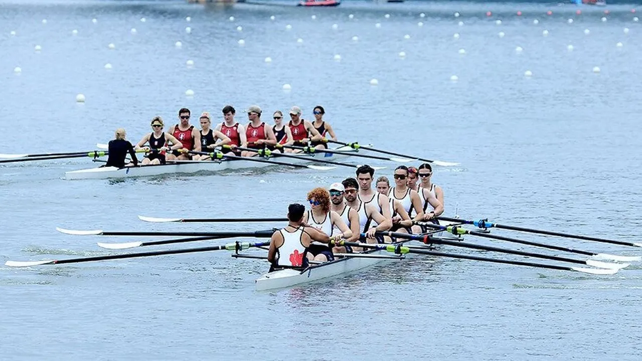 Two rowing crews race on a buoy-marked river.