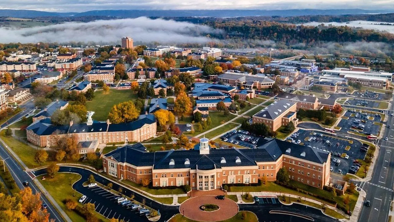 Aerial view of a college campus with brick buildings, autumn trees and low fog.