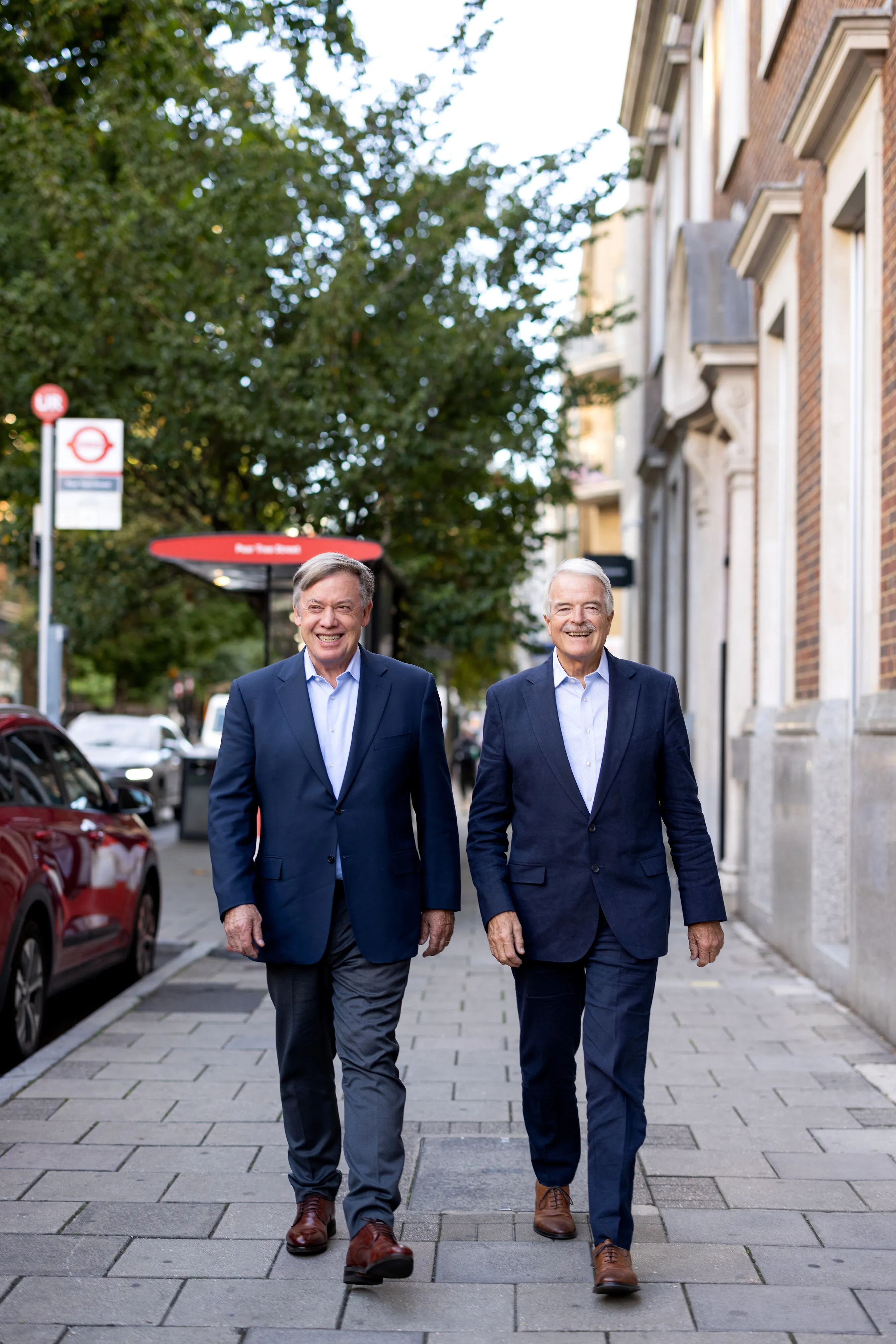 Michael Crow and Sir Malcolm Grant walk along a London pavement.