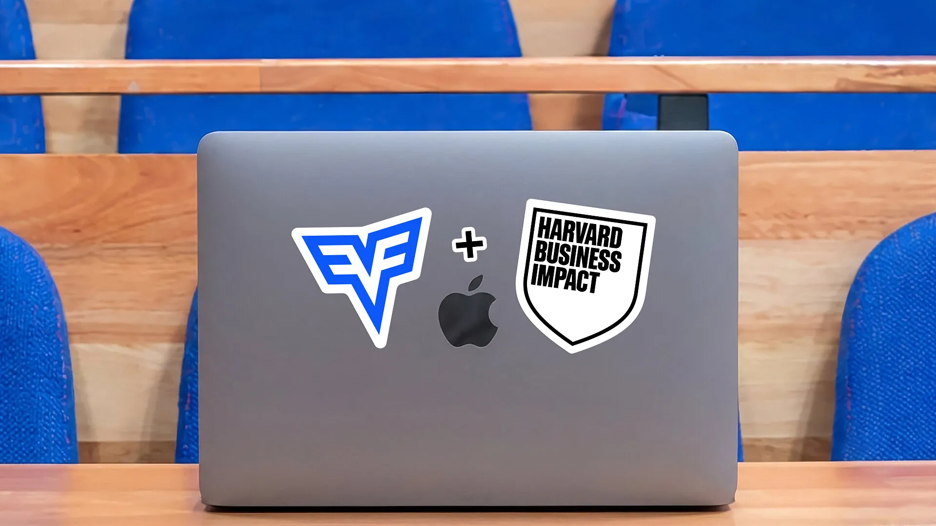 A laptop with CodeSignal and Harvard Business Impact stickers in a lecture hall.