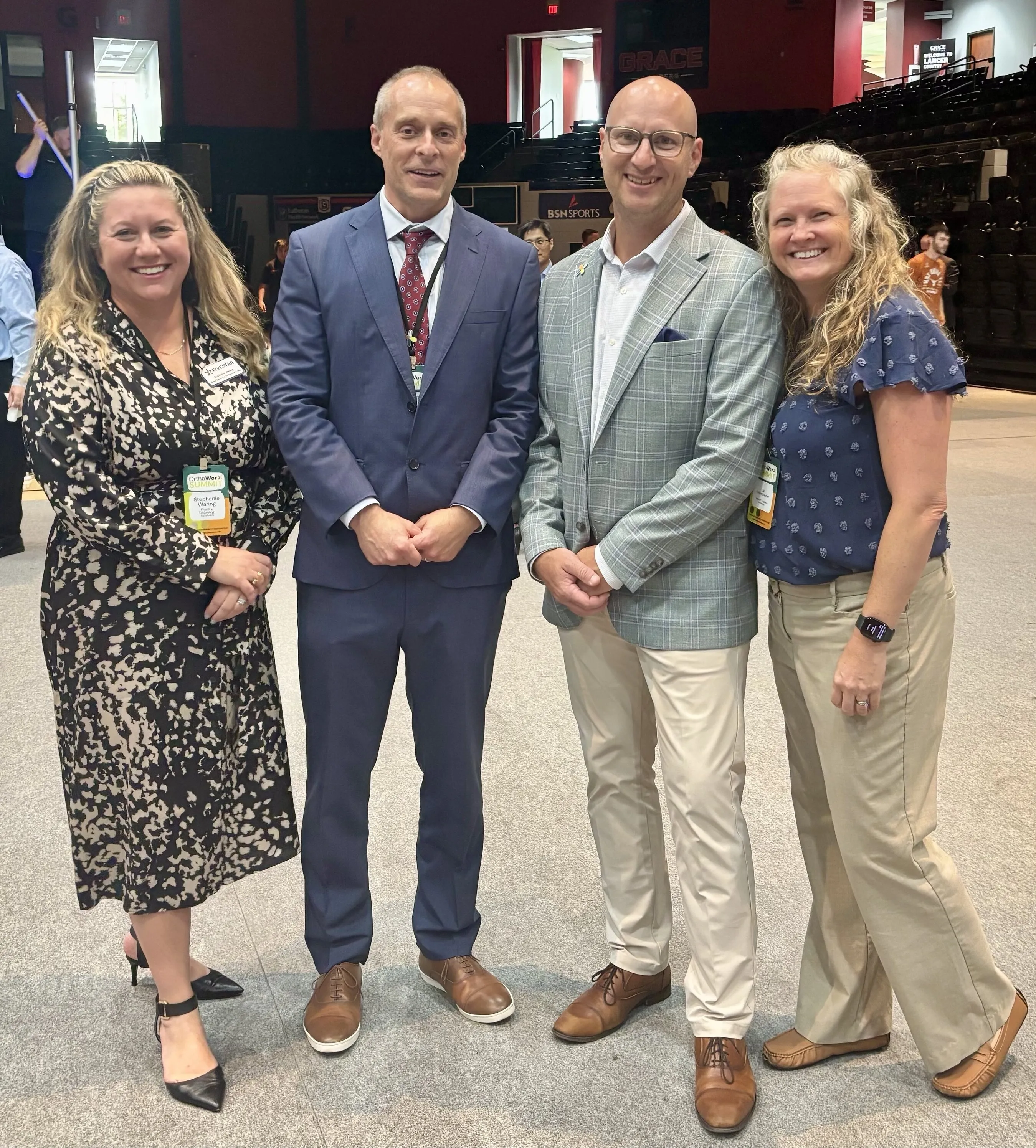 Four adults smiling together inside an auditorium.