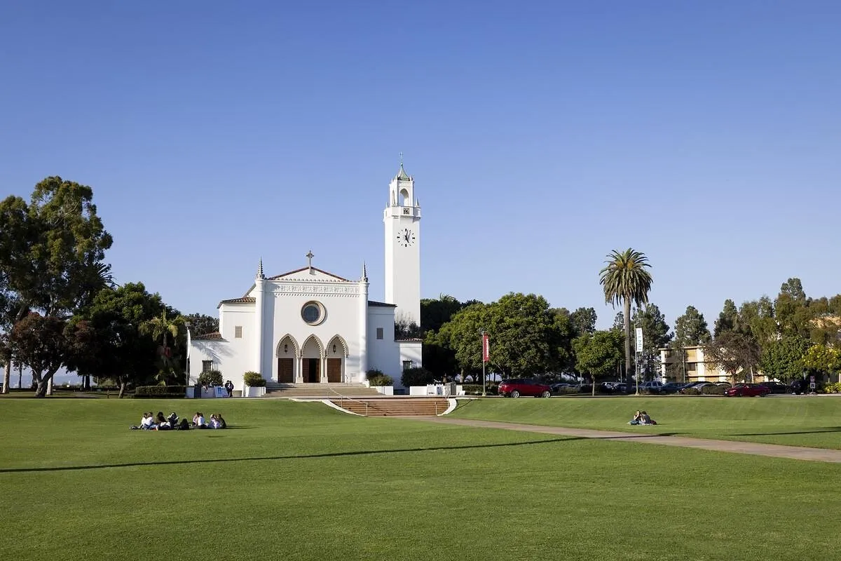 A white chapel and clock tower on a green university lawn