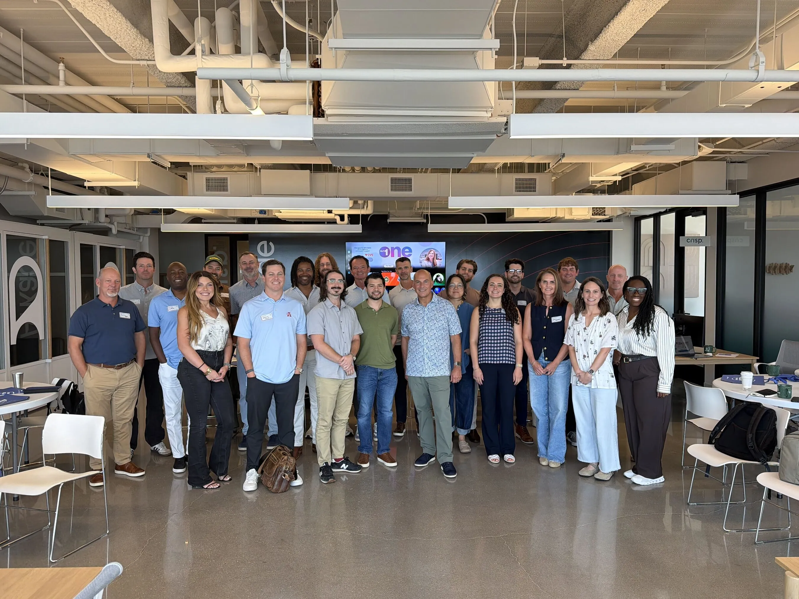 A group of people standing together in a modern office meeting space.