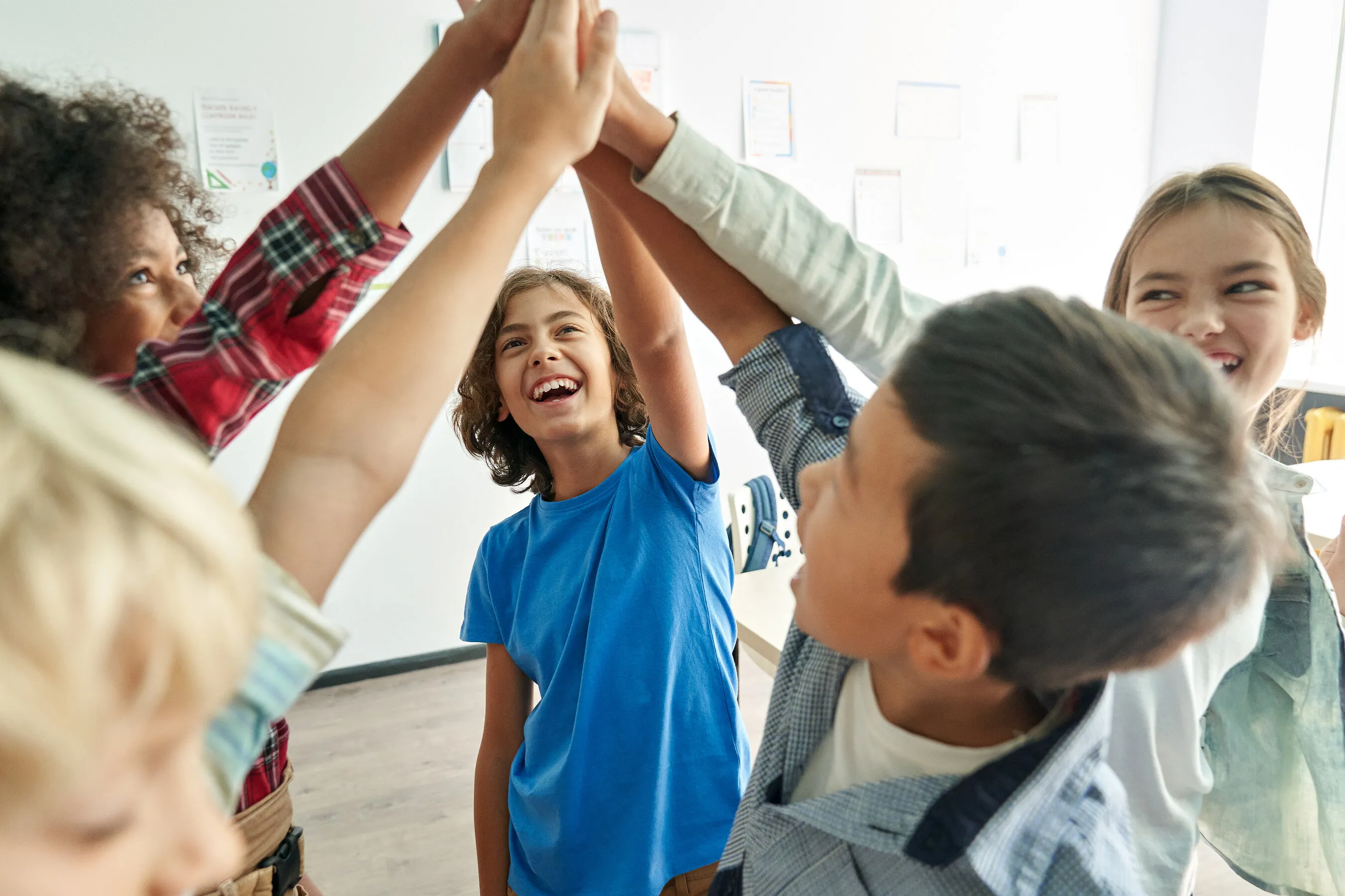 Children raising their hands together in a classroom.