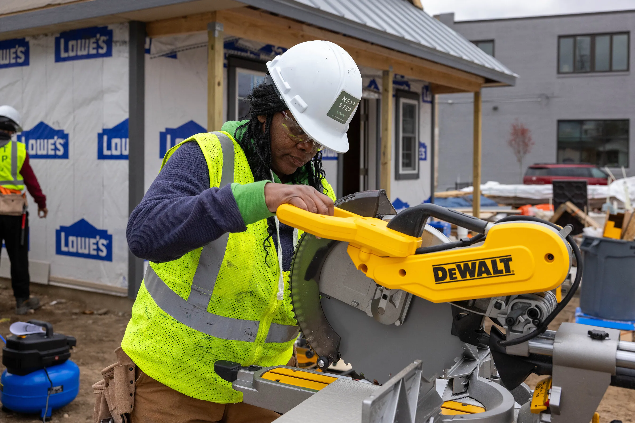 Construction worker using a DeWalt miter saw at a building site.