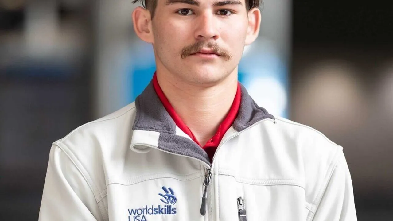 A man wearing a WorldSkills USA jacket over a red shirt.