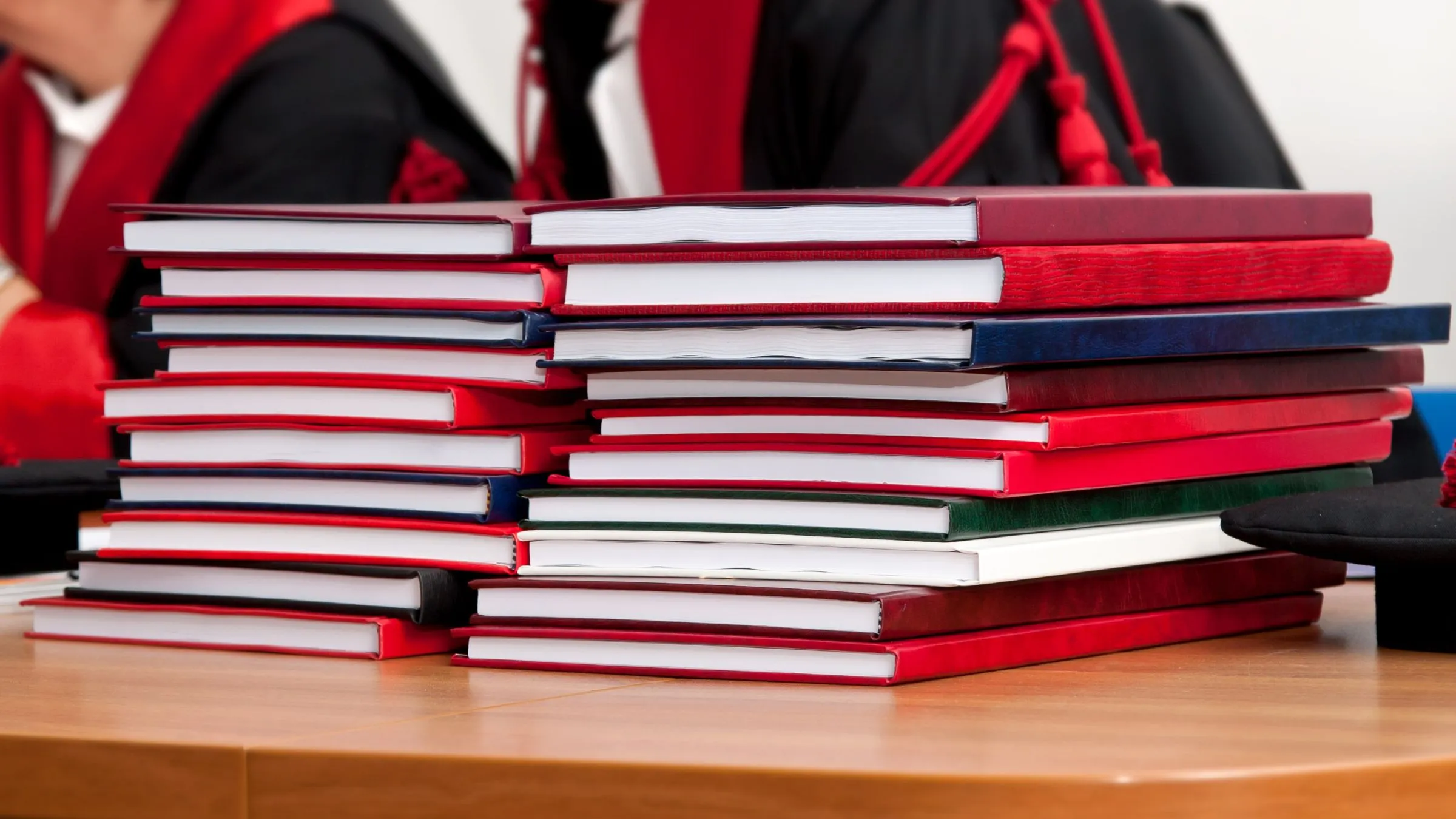 Stacks of bound theses in red and blue covers on a table
