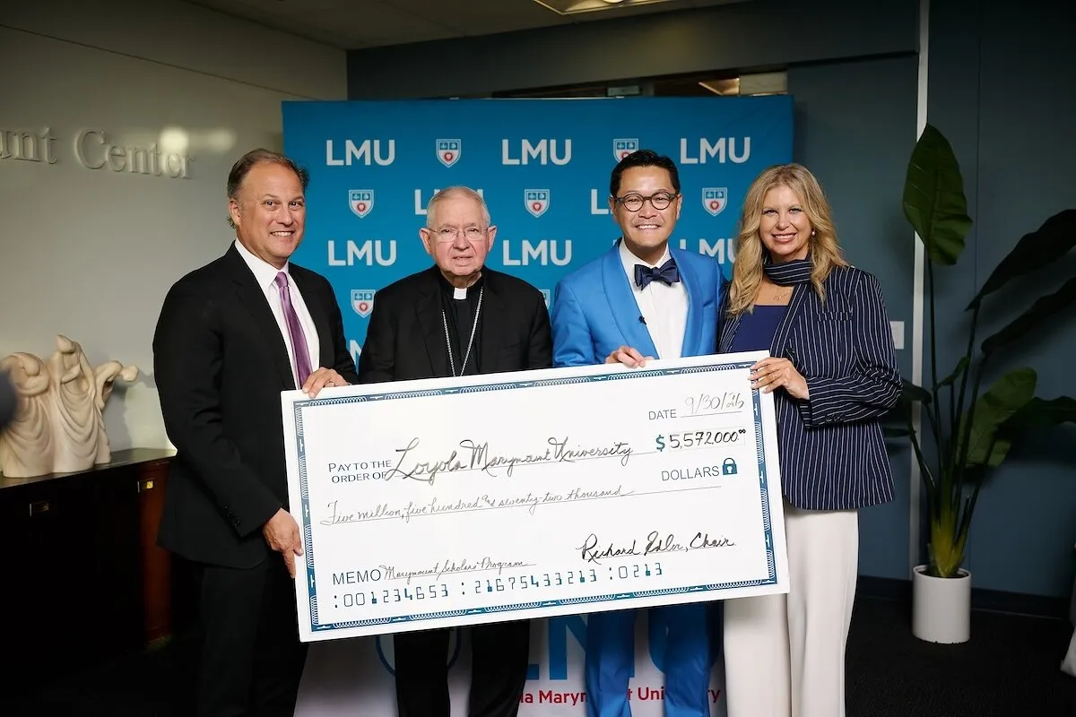 Four people hold a large ceremonial check in front of an LMU backdrop.